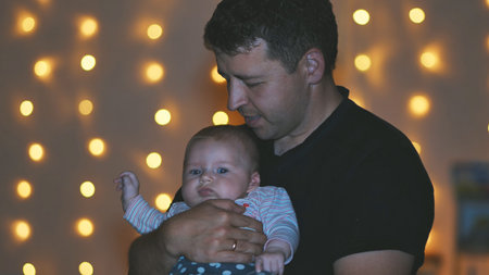 Loving father embracing newborn daughter, tender moment framed by softly glowing christmas lights,...