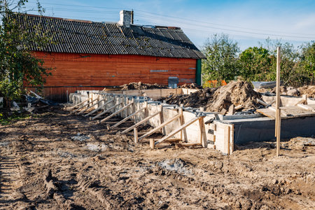 Building strip foundation for new house next to old wooden houseの写真素材