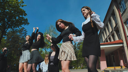 High school graduates celebrating their achievement and freedom with outdoor dancing and joyous...