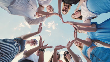School friends joining hands in a circle, representing unity, teamwork, and friendship under a...