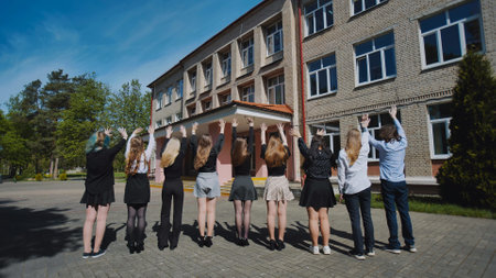 Group of happy students waving goodbye to their school on the last day, celebrating the end of the academic yearの写真素材