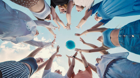 Students reaching for a globe, symbolizing global citizenship, environmental awareness, and international cooperation for a sustainable futureの写真素材