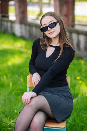 Stylish student enjoying a relaxing outdoor moment, exuding youthful confidence and fashionの写真素材