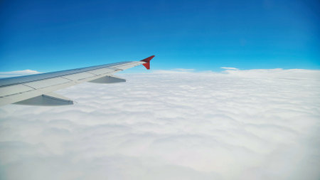Airplane wing gliding over pristine white cloudscape, revealing sweeping azure skies during tranquil aerial passageの写真素材