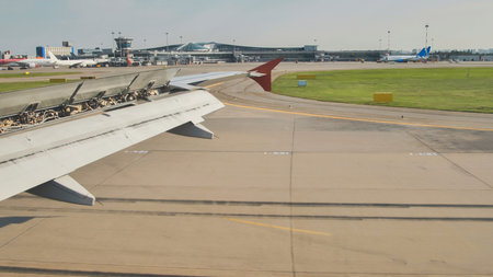 Airplane wing with open flaps approaching airport terminalの写真素材