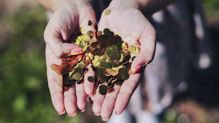 Woman spreading golden confetti, celebrating momentous milestone with joyful gesture during festive personal achievementの写真素材