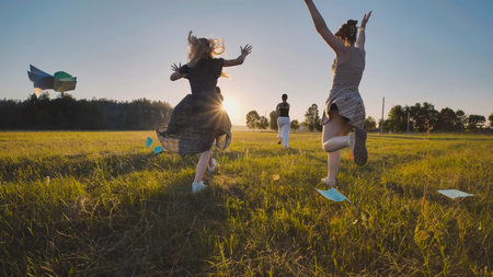 High school girls running in a field throwing papers in the air at sunset, celebrating the end of...