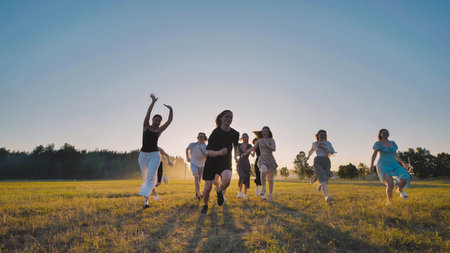 High school students are happily frolicking in a field at sunset, embracing the carefree joy of...