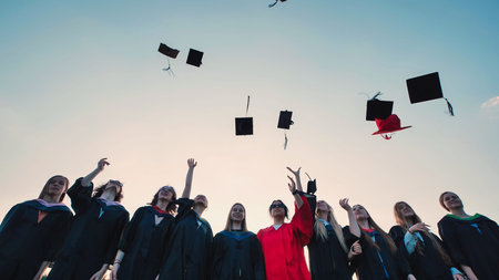 Happy students in graduation gowns tossing caps in the air to celebrate their academic achievements