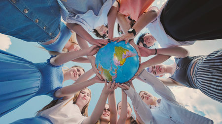 School friends unite in support of environmental awareness, global citizenship, and international cooperation by holding a globeの写真素材