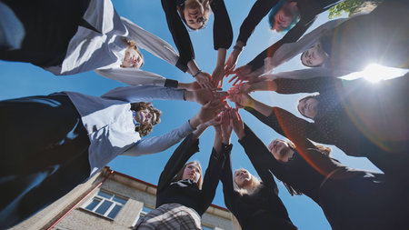 Students joining hands in a circle to represent unity, teamwork, and collaboration in an educational...