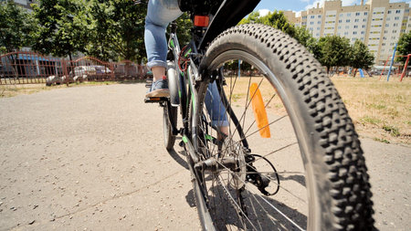 A twelve-year-old girl riding her bike on a warm summer day. Bicycle wheel close up.