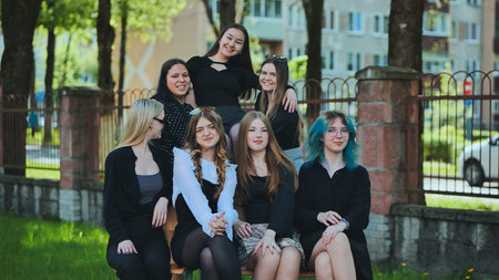High school students having fun together, goofing around on a bench in the schoolyard during a break
