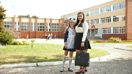 Two Russian schoolgirls sisters posing in festive clothes on the day of the beginning of the school...