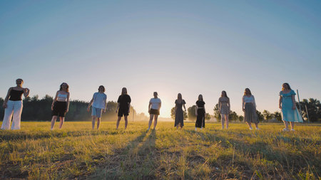 Young high school students basking in the warm glow of the setting sun in a field during summer...