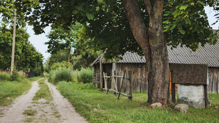Serene countryside scene featuring a dirt road leading towards an old wooden barn under a leafy tree