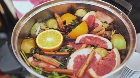 Chef preparing mulled wine with various fruits and spices in a potの写真素材