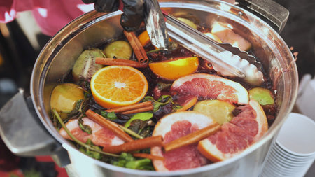 Mulled wine simmering in pot with cinnamon sticks, orange and grapefruit slicesの写真素材