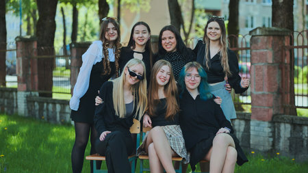Happy students posing together on a schoolyard bench, enjoying their dayの写真素材