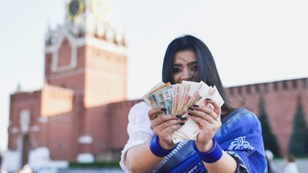 Bangladeshi woman holding russian rubles and US dollars in Moscow Red Square