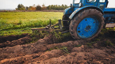 Blue tractor plowing the field in autumn.の写真素材