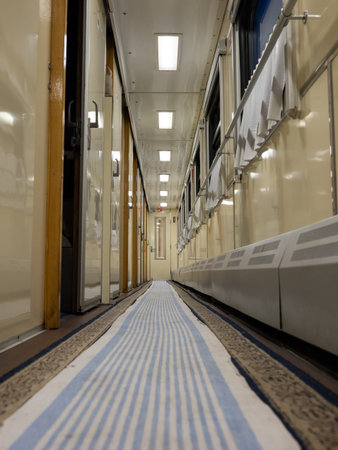Train journey corridor presenting empty pathway with blue striped runner carpet