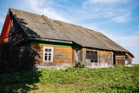 Old abandoned wooden house with broken windows and damaged roof is collapsing in countryside