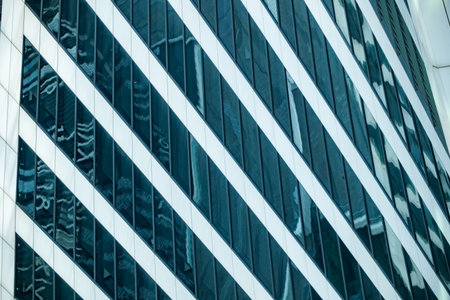 Modern glass facade with diagonal white lines reflecting surrounding city