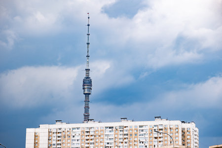 Ostankino television tower peaking over a residential building in Moscow under cloudsの写真素材