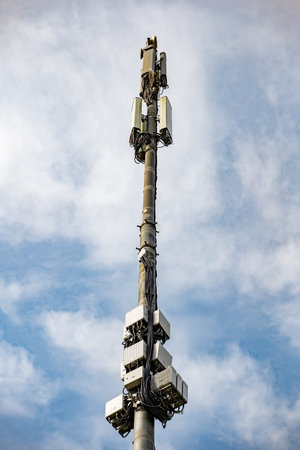 Cell tower providing 5G mobile telecommunication connectivity against cloudy sky