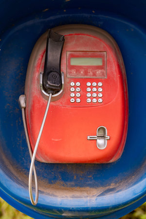 Abandoned red payphone inside a weathered blue booth illustrating outdated communicationの写真素材