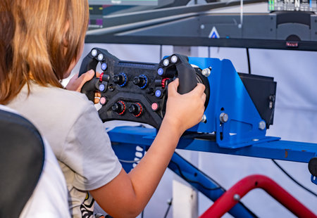 Young boy playing a racing simulator steering wheel, enjoying competitive video gameの写真素材