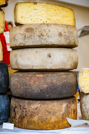 Stacked aged cheese wheels displaying rustic texture and ready for market sale