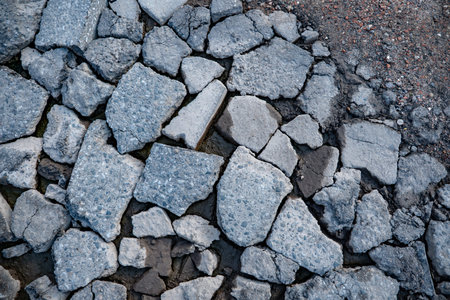 Broken asphalt pavement fragments creating a textured surface backgroundの写真素材