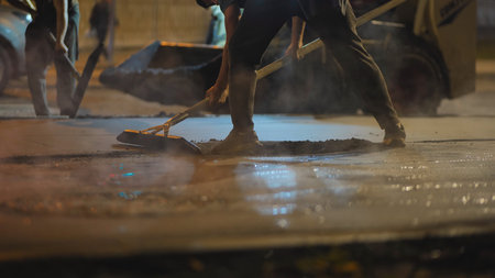 Night road repair crew working, laying fresh hot asphalt on a streetの写真素材