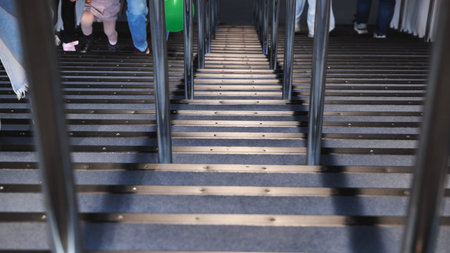Travelers ascending and descending a wide modern staircase with metal railings