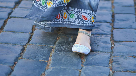 Bangladeshi woman wearing traditional dress walking on cobblestone street