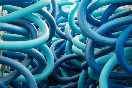 Tangled blue pool noodles forming an abstract pattern with intertwining curvesの写真素材