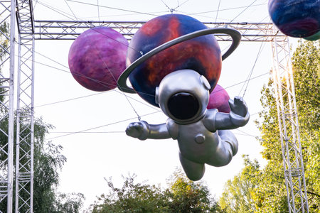 Astronaut sculpture flying through cosmic outdoor display with colorful planets