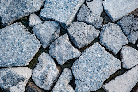 Broken asphalt creating abstract texture of destruction and decay on urban surface