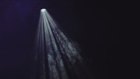 Theatrical spotlight shines through smoke on a dark stage background