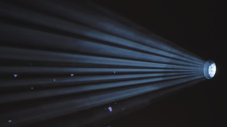 Projector light beam with visible blue rays shining through dark, hazy air.