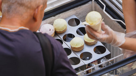 Customer buying ice cream cone from vendor at outdoor freezer in summerの写真素材