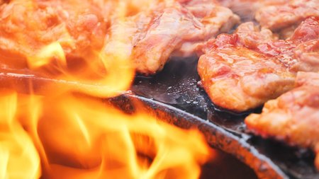 Grilling meat on a barbecue with open flames, cooking for a delicious summer meal