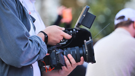 Person focusing camera lens, filming outdoor video content with professional equipment