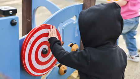 Child playing with a red and white spinning toy at an outdoor playgroundの写真素材
