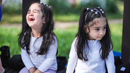 Little sisters laughing and observing, enjoying childhood moments outdoors