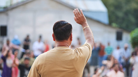 Man from behind waving to crowd during Ganesh Chaturthi festival celebration