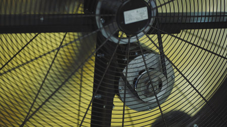 Close up view of an industrial fan operating, spinning blades creating air movement