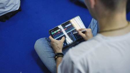 Person mixing audio on a tablet using a stylus, doing sound engineering remotely